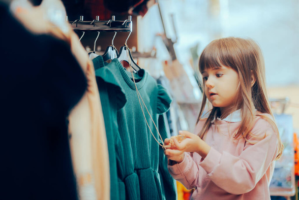 Little Girl Checking the Accessory of a Dress on the Rack  - Valokuva, kuva