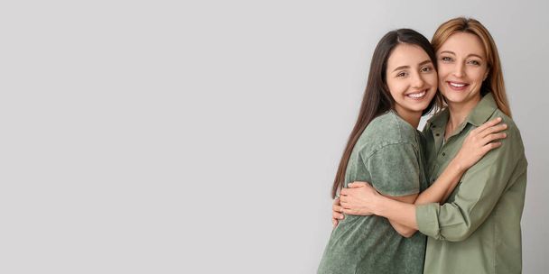 Portrait de jeune femme heureuse et mère sur fond gris avec espace pour le texte - Photo, image