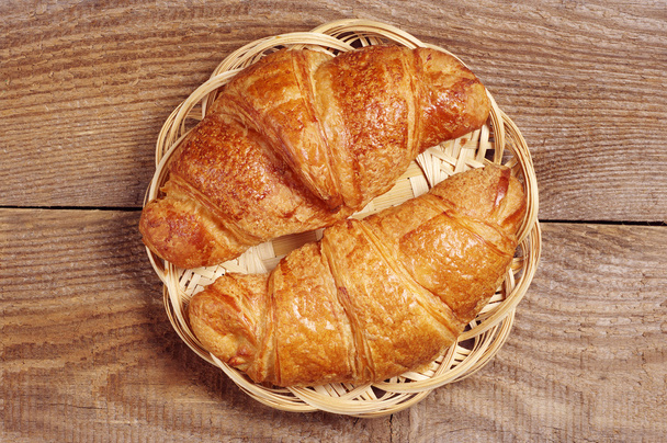Two fresh croissants in wicker plate  - Photo, Image