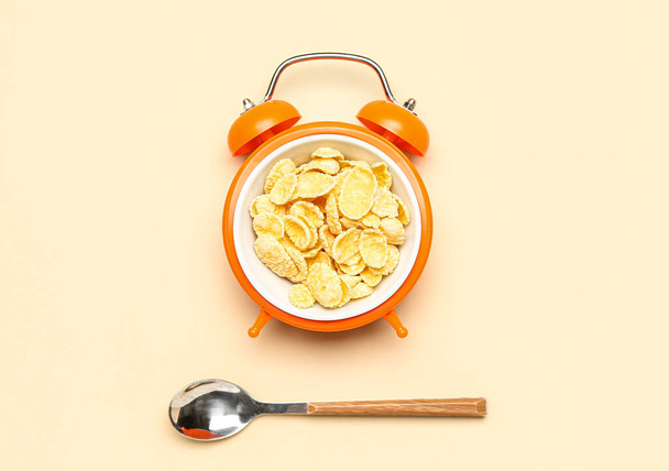Creative composition with alarm clock, corn flakes and spoon on color background - Foto, Imagen