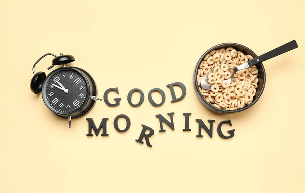 Renkli arkaplanda Good Morning, alarm clock ve bir kase mısır gevreği halkası içeren kompozisyon - Fotoğraf, Görsel