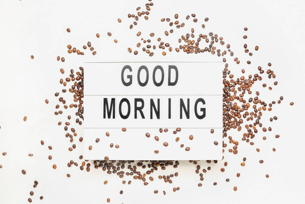 Tabule s textem Dobré ráno a kávová zrna na světlém pozadí - Fotografie, Obrázek