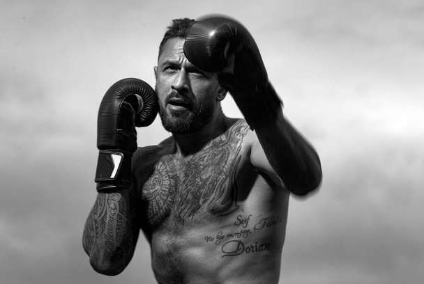 Boxer practicing punches in boxing. Boxer punching in boxing gloves. Sporty man during boxing exercise. Strength and motivation. Strong muscular boxing man - Foto, imagen