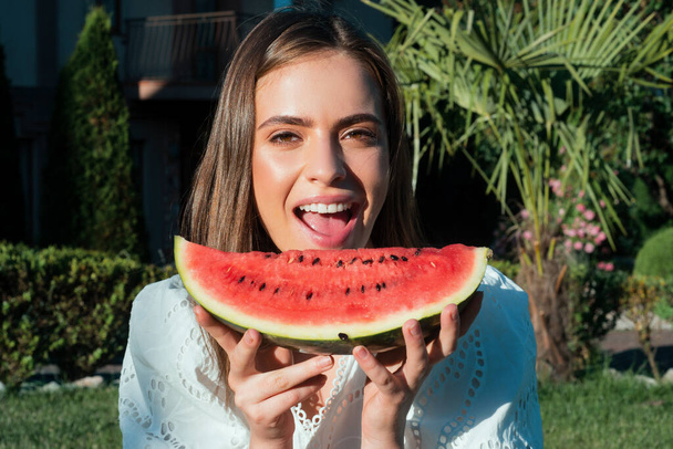 Closeup portrait of young sensual woman eating watermelon. Happy young woman with watermelon in park - Foto, immagini