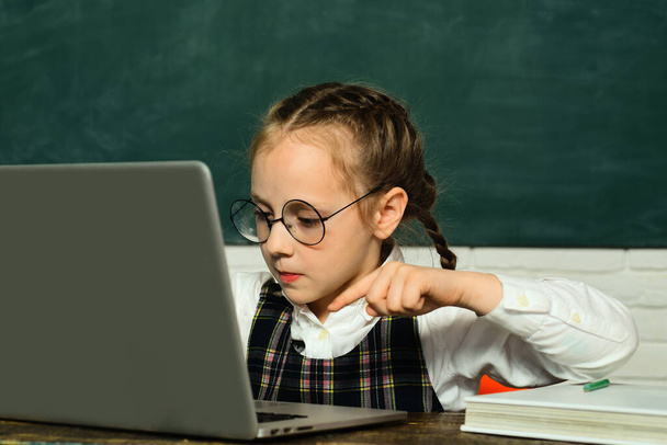 Back to school. Pupil working on laptop computer over blackboard background. Chalkboard copy space - school concept - Фото, зображення