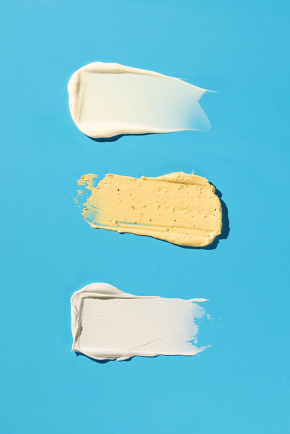 Samples and textures of various cosmetics for skin and hair care on a blue background. Swatches. Skin care. - Foto, Imagen