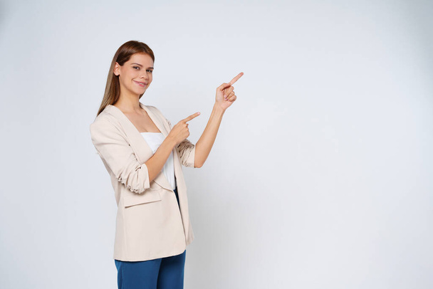 Young mixed race woman pointing to empty copy space isolated on white background. - Fotoğraf, Görsel