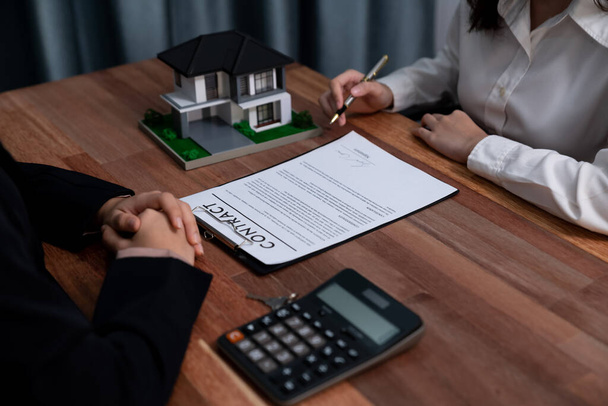 Completing the final step of the house loan process, the buyer signs the loan contract paper with a pen on the desk, securing the ownership of the property. Enthusiastic - Photo, Image
