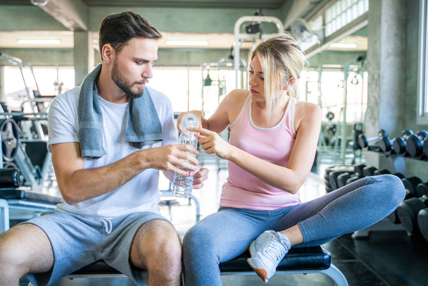 Happy couple drinkking water after exercise in sport fitness gym happy relationship - Fotó, kép