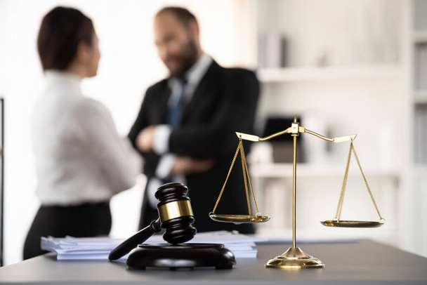 Balanced scale of justice and gavel hammer in focus on blurred background of lawyer colleagues discuss and plan for lawsuit in law firm office, as legal representatives. Equilibrium - Photo, Image