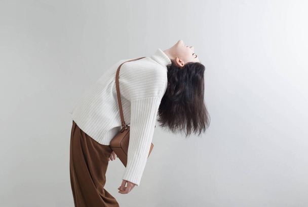 modern girl in white sweater and brown pants in white room - Photo, Image