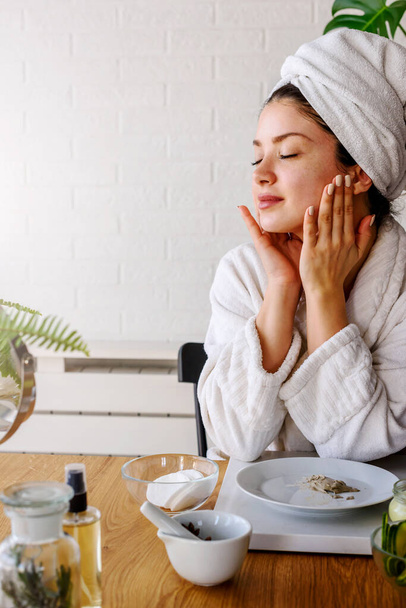 mooie jonge vrouw met handdoek op haar hoofd maken dagelijkse huidverzorging routine - Foto, afbeelding
