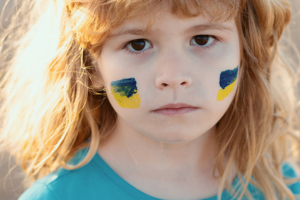 Ukraine flag on kids cheek. Little ukrainian patriot - 写真・画像