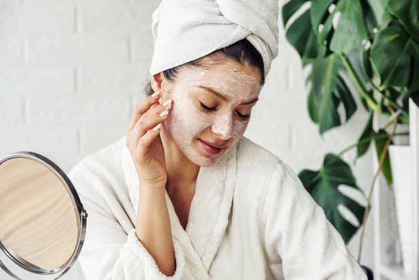 mooie jonge vrouw met handdoek op haar hoofd maken dagelijkse huidverzorging routine - Foto, afbeelding