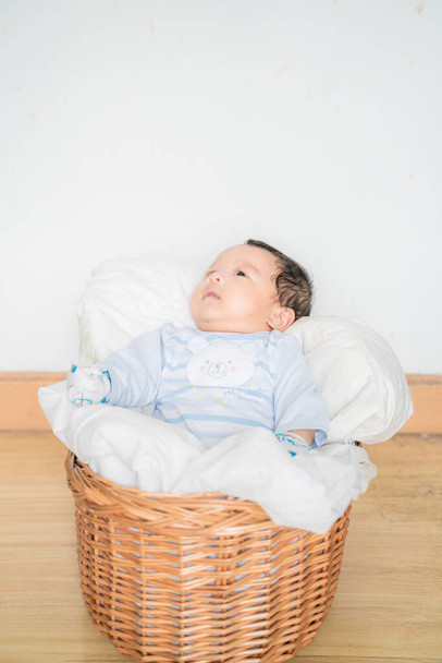 Новорожденный мальчик лежит на одеяле в деревянной корзине вид сверху азиатский мальчик - Фото, изображение