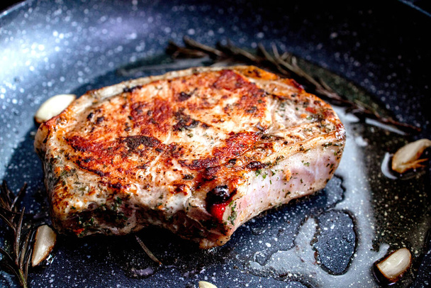 Grilled premium rib eye beef steak in the pan, cooking steak in the kitchen on a dark background. Overhead shot of chef preparing ribeye with butter, thyme and garlic - Foto, Bild