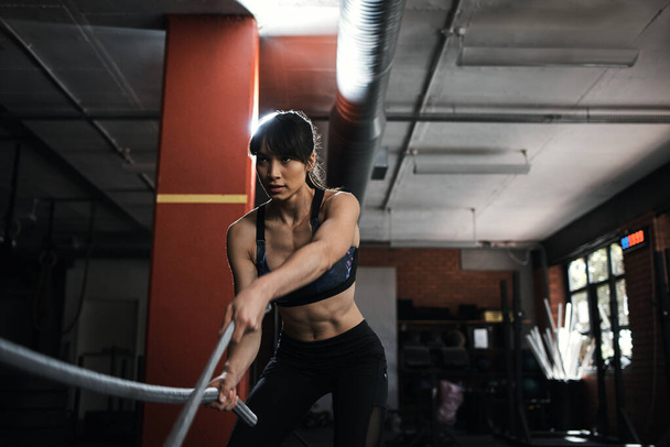 Будьте рішучими. молода жінка робить важку підготовку мотузки в спортзалі
 - Фото, зображення