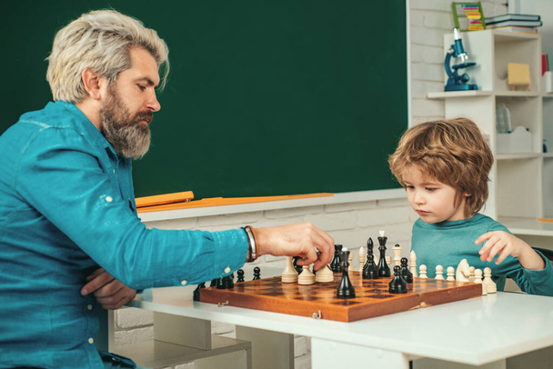 Father with son playing Chess at home. Happy two generations of men have fun and playing Chess. Cute little boy playing chess with Parents - Valokuva, kuva