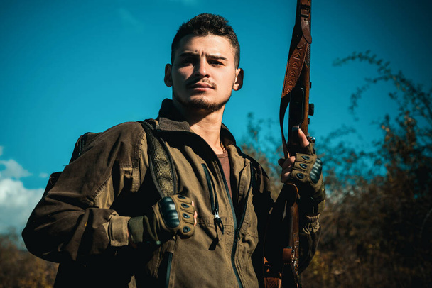 Close up Portrait of hamdsome Hunter. Poacher with Rifle Spotting Some Deers. Illegal Hunting Poacher in the Forest. Hunter with shotgun gun on hunt - Фото, зображення