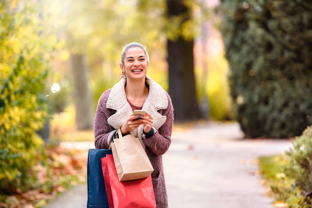 beautiful young woman walking in the park with shopping bags - Foto, Imagen