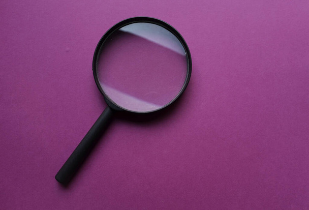 cadre noir une loupe sur forme rectangulaire papier coloré fond blanc et violet - Photo, image