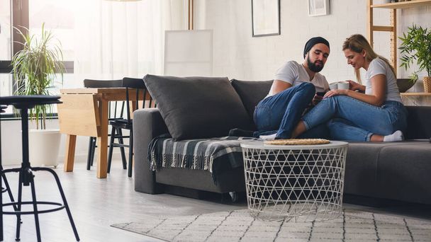 couple sitting on sofa and drinking coffee - Photo, Image