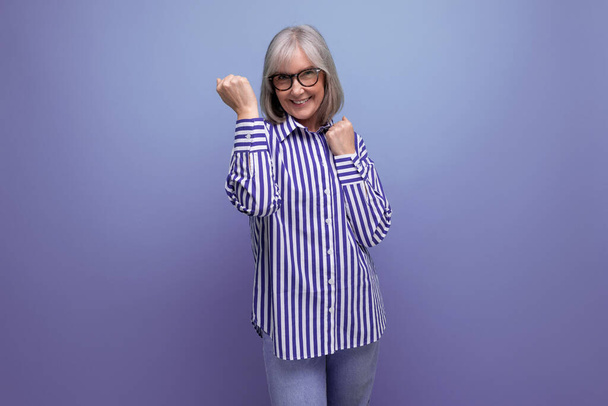 bem sucedido alegre 60s mulher de meia-idade na camisa da moda no fundo brilhante estúdio com copyspace. - Foto, Imagem