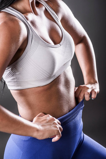portrait of sexy sportswoman with muscular body isolated on dark background - Φωτογραφία, εικόνα