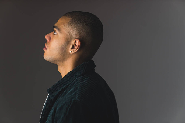 Side profile shot of young African American man with buzz cut on a grey dark studio background . High quality photo - Photo, Image
