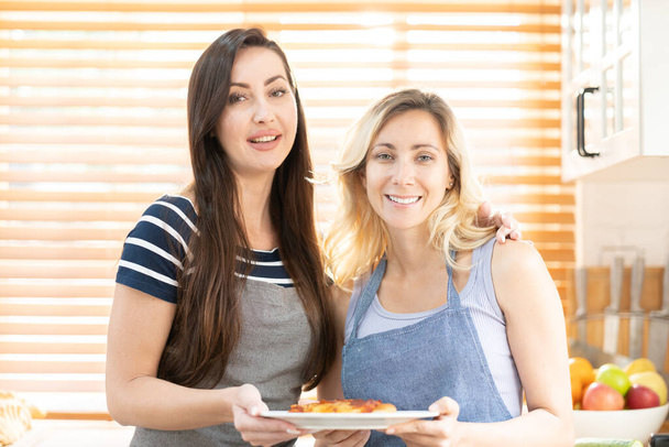 Due donne caucasiche che cucinano la pizza insieme in cucina. Il concetto di cibo cucinato in casa e relazioni LGBT. concetto di famiglia e diversità. lgbt amore. - Foto, immagini