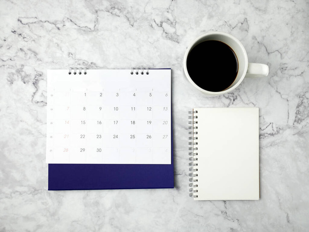 Calendario con taza de café sobre fondo de textura de mármol. - Foto, imagen
