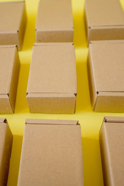 Many cardboard kraft boxes on a yellow background. Packing the parcel - Φωτογραφία, εικόνα