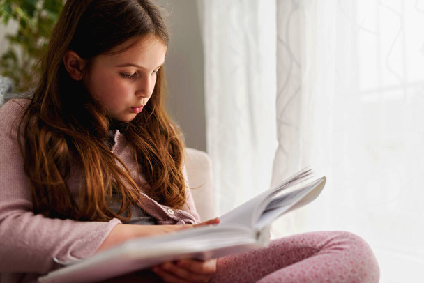 a young girl reading her book in the living room - Photo, Image