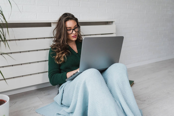attractive young woman sitting on floor and typing on laptop  - Photo, Image