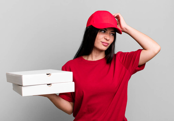 hispanic pretty woman smiling happily and daydreaming or doubting. delivery pizza concept - Фото, изображение