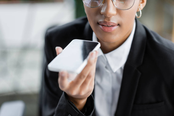 vista cortada de empresária afro-americana enviando mensagem de voz no celular no escritório - Foto, Imagem