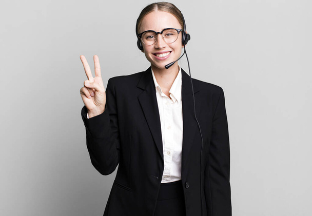 caucasian pretty woman smiling and looking friendly, showing number two. telemarketing concept - Foto, Imagen