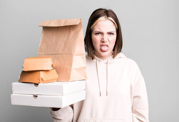 young pretty woman feeling disgusted and irritated and tongue out. take away fast food concept - Fotografie, Obrázek
