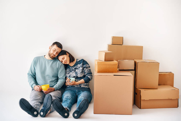 Happy carefree couple having break during moving to new house and relaxing on the floor enjoy their apartment. Real estate, moving day, new life concept - Photo, Image
