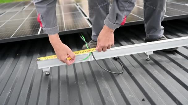 Nahaufnahme eines kompetenten Technikers, der Messungen für exakte Berechnungen vornimmt. Anpassung von Solarzellen auf einem Dach. Ingenieur im Helm berechnet Solarzelle mit Maßband. - Filmmaterial, Video