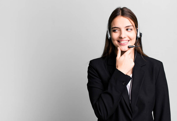 young pretty woman smiling with a happy, confident expression with hand on chin. telemarketing agent concept - Photo, image