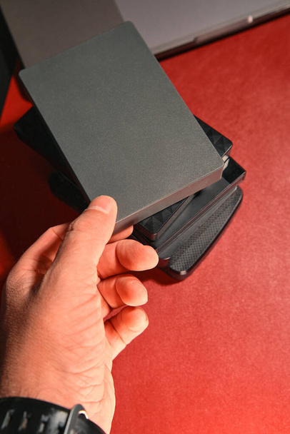 Ένα χέρι παίρνει ένα εξωτερικό σκληρό δίσκο από ένα σωρό, κοντινό πλάνο - Φωτογραφία, εικόνα