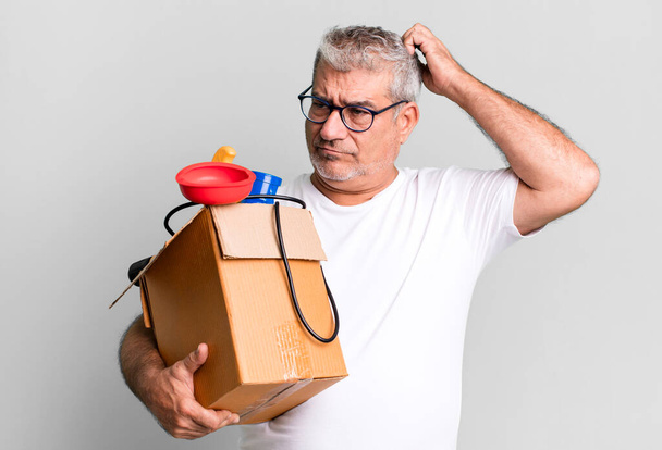 middle age senior man feeling puzzled and confused, scratching head. housekeeper repairman with a toolbox concept - Zdjęcie, obraz