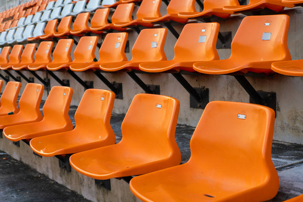 Oranje witte stadion stoelen in outdoor veld sport achtergrond - Foto, afbeelding