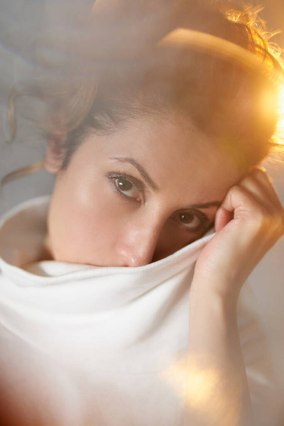 Warm light close-up portrait concept. Emotional looking young woman looking at camera, thinking and dreaming of something. High quality vertical photo - Foto, Imagen