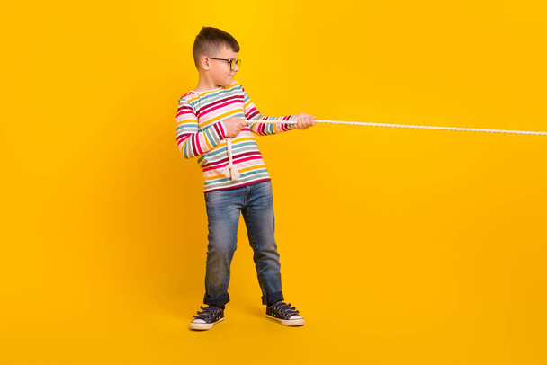 Full profile side photo of sweet kid boy playing outdoors pull string isolated on vibrant color background. - Foto, Imagem