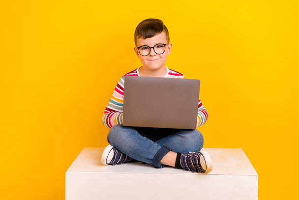 Photo of smart clever schoolkid wear stylish clothes sitting cube learning online homeschooling isolated on yellow color background. - Foto, Imagen