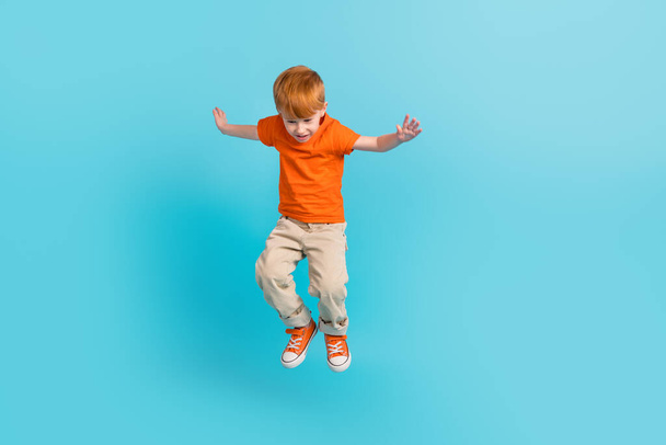 Täyspitkä kuva iloinen hullu poika pukeutua oranssi trendikäs vaatteita katsoa alas juhlia myynti eristetty syaani väri tausta. - Valokuva, kuva
