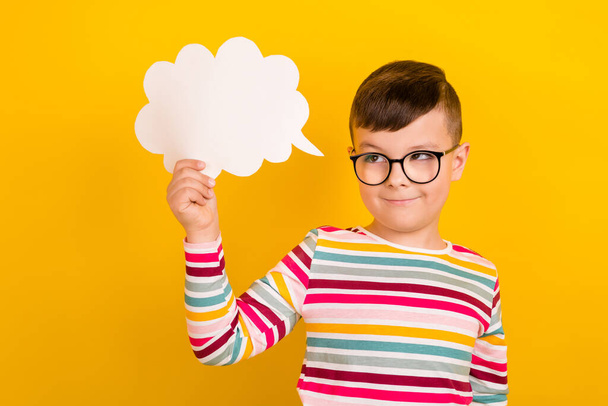 Photo of smart clever boy wear striped trendy clothes hold cloud card tell comment look empty space isolated on yellow color background. - Foto, immagini