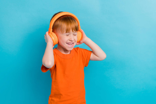 Zdjęcie wesołego pozytywnego zadowolony ładny chłopiec słuchać muzyki odtwarzacz mp3 puste miejsce izolowane na tle koloru cyjan. - Zdjęcie, obraz